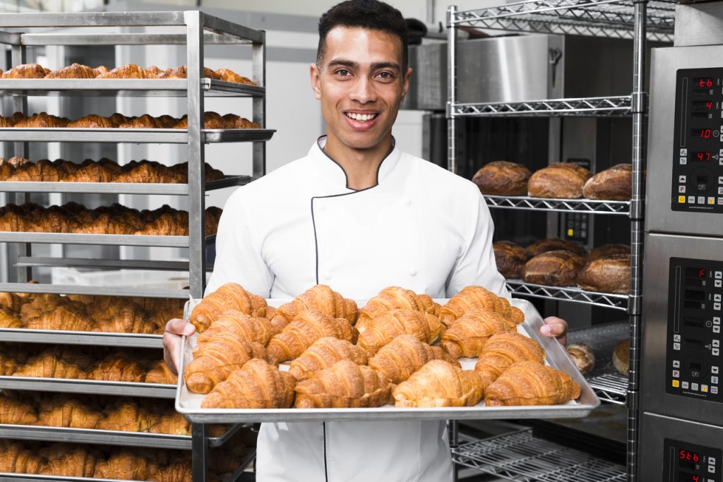 A baker holding up bread from the oven