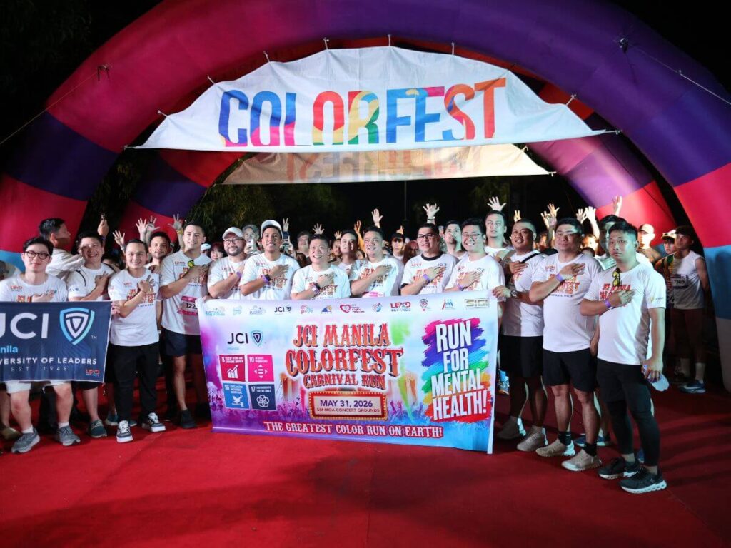 JCI Manila members and event partners posing beneath the Colorfest arch with a Run for Mental Health banner