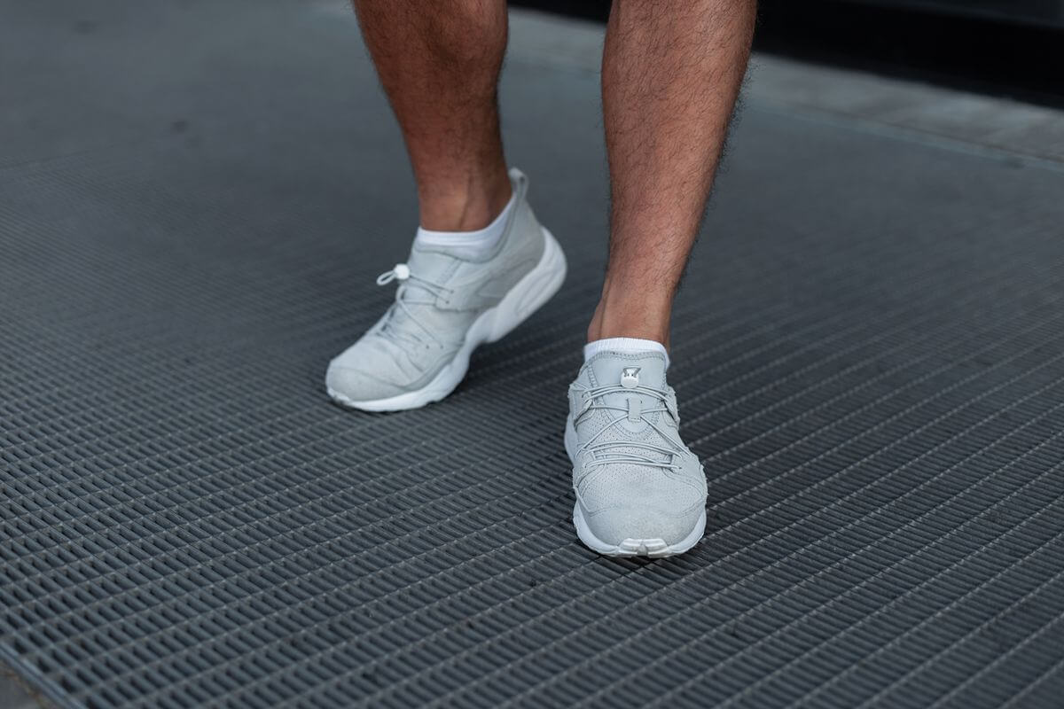 Close-up of a worker wearing white shoes on a textured floor in an industrial environment