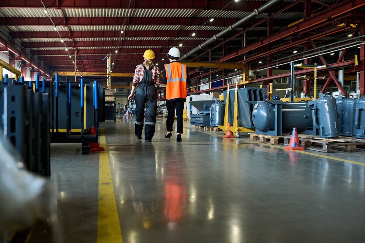 Workers walking through an industrial manufacturing facility with specialized flooring and electrical equipment